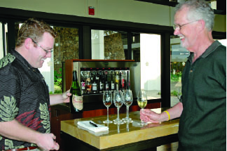 Wine manager Brian Clancy (left) tells a guest how a growing region has as much to do with the style and flavor of wine as how it’s made.
