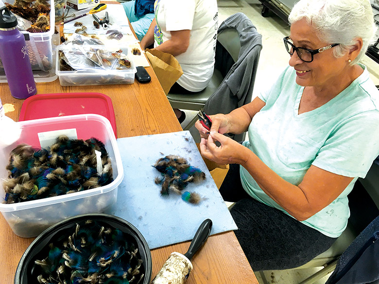 Yvonne Bento sorts feathers before beginning construction of a lei hulu.
