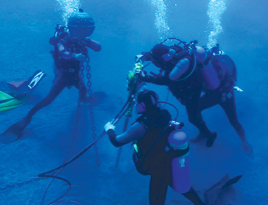 Divers work as a team to install a DUM, using lift bags to prevent coral damage.