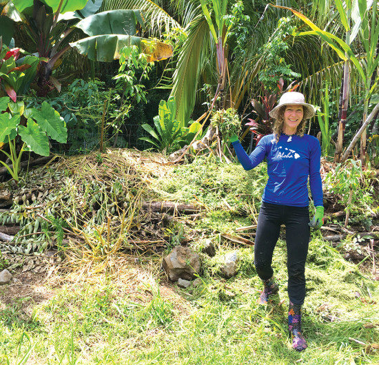 Farm helper Analeah uses chop-and-dropped branches and cut grass to mulch a "hugelkulture" mound planted with Cuban red banana, cassava, kalo, coconut, katuk, ti, and sugarcane. photo courtesy of Rachel Laderman