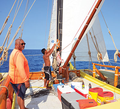 Crew member, Mana‘o Ikeda, raises the sails while Captain Chadd Paishon sets the course.
