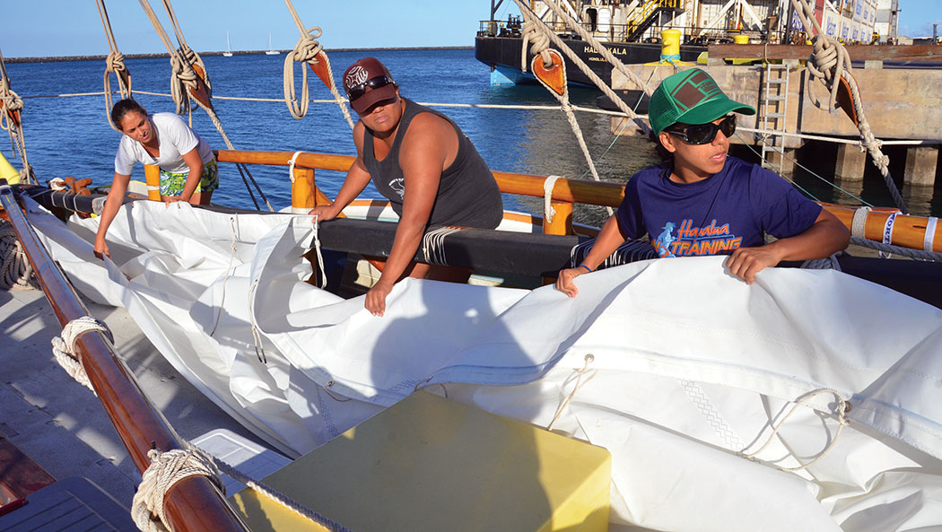 Kim Bennett, Loyal Baisa, Kanana Kuhaulua attach the mainsail to the mast and boom. 