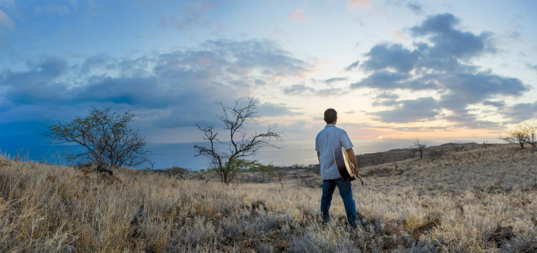 Mark with his guitar, watching the sunset from North Kohala. photo courtesy of Mark Saito