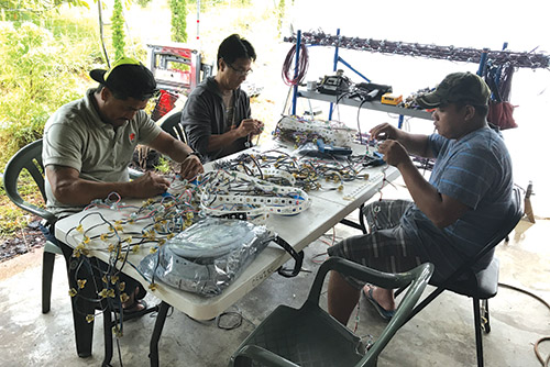 Stanward enlists the help of friends in creating the light displays. Here two of his buddies lend a hand during the 2017 Christmas season. photo courtesy of Stanward Oshiro