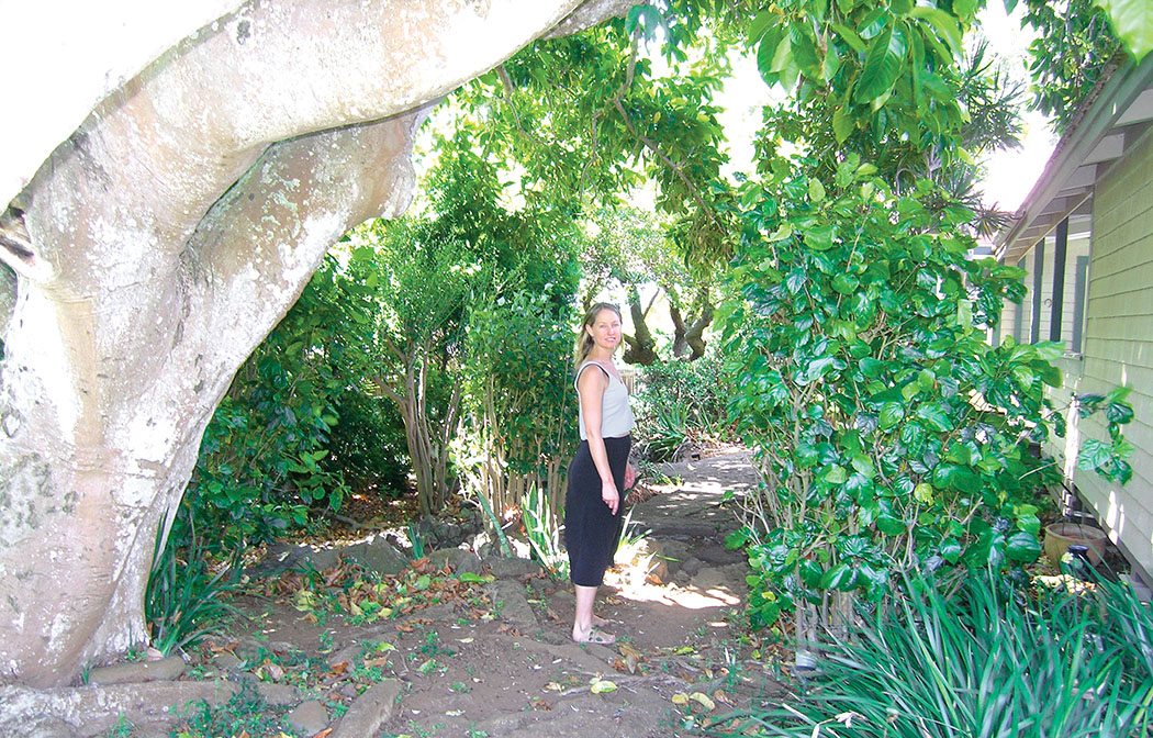 Leandra Rouse walks along the path with the 100-year-old ylang ylang tree. 