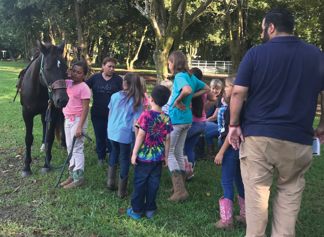 4-H volunteer Tutti Brennan shows Hands and Hearts of Kohala 4-H‘ers how to properly saddle a horse. photo courtesy of Lachelle Crabbe