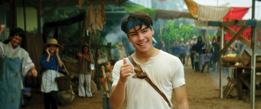 Ryan Potter, who plays Jo in the film "Running for Grace." Local “extras” are seen in the background. photo courtesy of the Hawai‘i Island Film Office