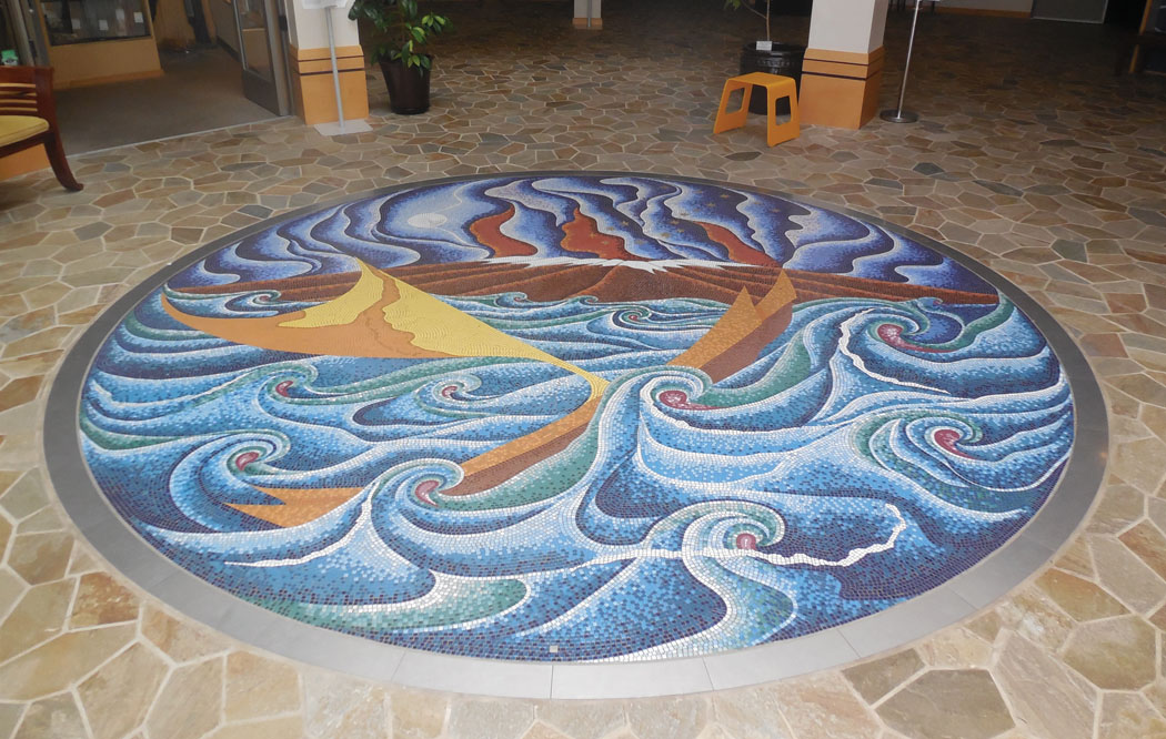 Circular mural of tiny painted tiles set into the floor of ‘Imiloa’s entrance. A voyaging canoe is depicted rocking in rough seas, with a steaming snow-capped mountain in the background set against a full-moon night and the constellation known to Polynesians as Mānaiakalani—Maui’s Fishhook. photo by Stefan Verbano