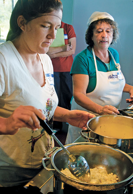 Vicki Dunaway (right) supervises as Zavi Brees is slicing the curd.