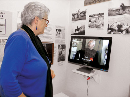 Momi pointing out a video display of “talk stories” with prominent paniolo that can be viewed while visiting the permanent exhibit. photo by Jan Wizinowich