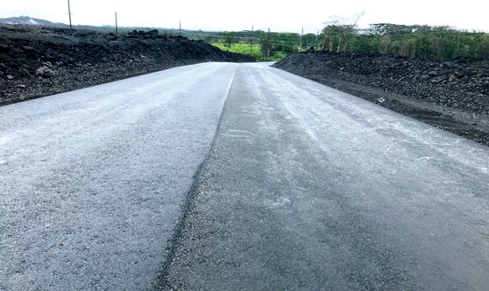 A freshly-paved stretch of the new upper section of Highway 132 with banked shoulders of lava cinders, September 2019. photo courtesy of Hawai‘i County Department of Public Works
