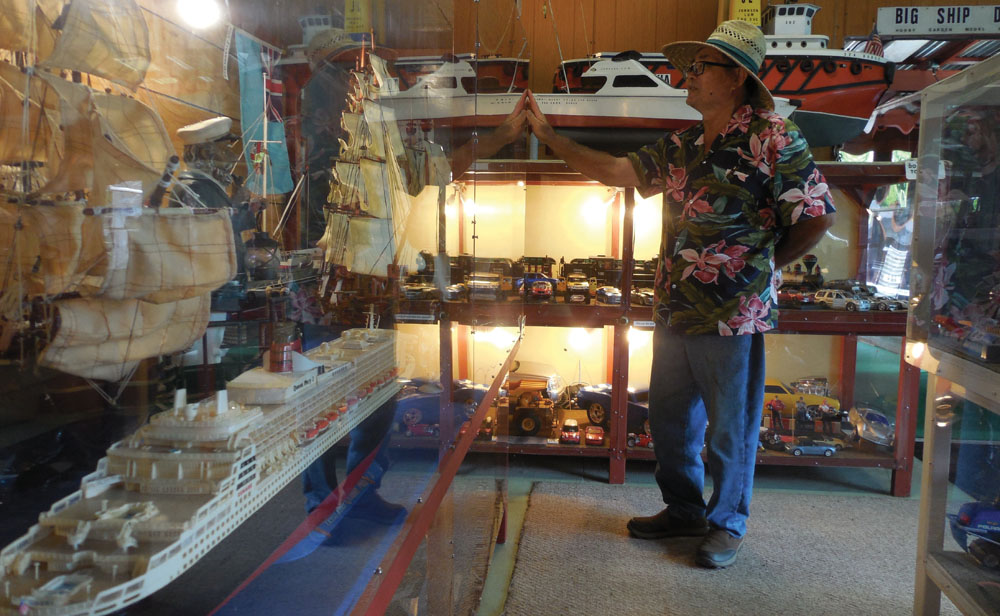 Johnson Lum looks over a display case in “The Wow Room” filled with models of seagoing ships throughout modern history. 